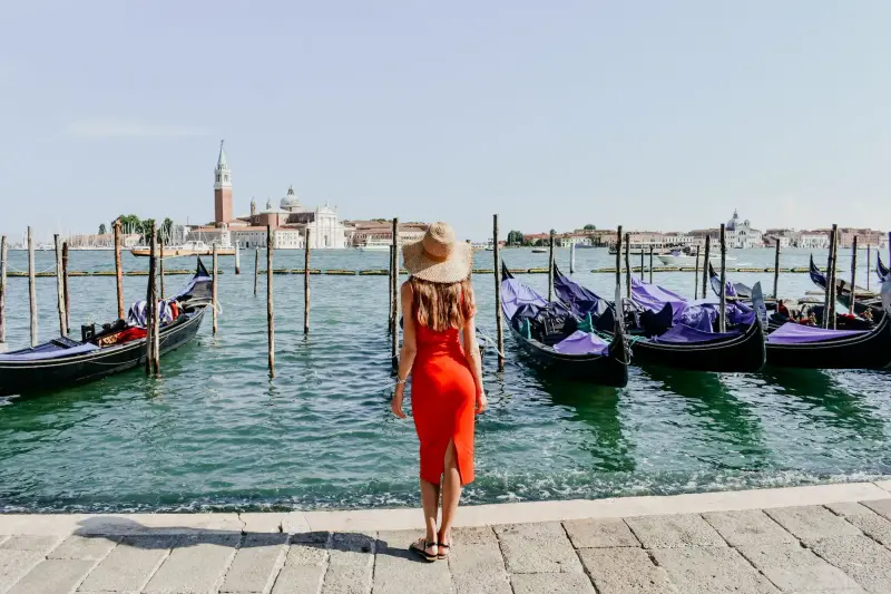 A high-class escort companion on the Venice waterfront with gondolas and the lagoon in view