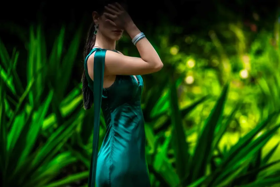 Luxury escort in Australia in an elegant green dress surrounded by tropical nature