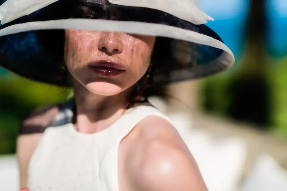 High-class escort Latem: elegant escort in a wide-brimmed sun hat and white dress